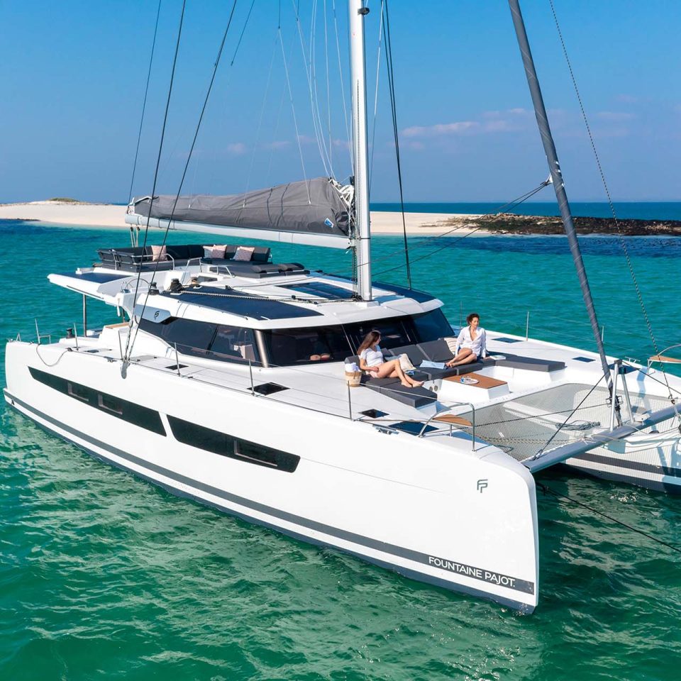 Fountaine Pajot Aura 51 electric sailing catamaran at anchor near beach