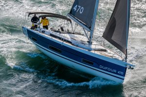 Dufour 470 smart electric monohull under brisk sail with man at helm