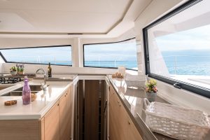 Large light wood kitchen with wrap around windows aboard the Bali 5.4