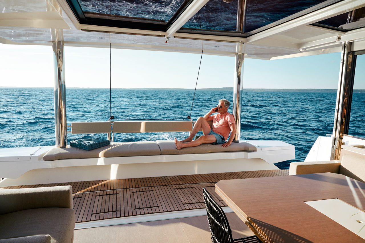 Man sitting on transom bench seating on the Bali 5.4 sailing catamaran overlooking sea