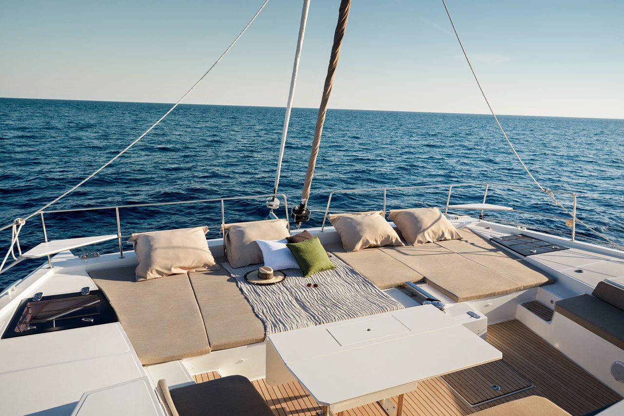 Front deck of the Bali 5.4 with cushioned sun lounge and dining table