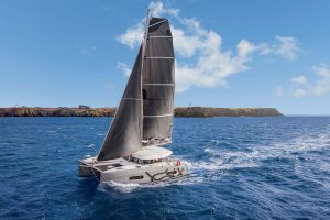 Excess 11 catamaran at full sail with green island in distance