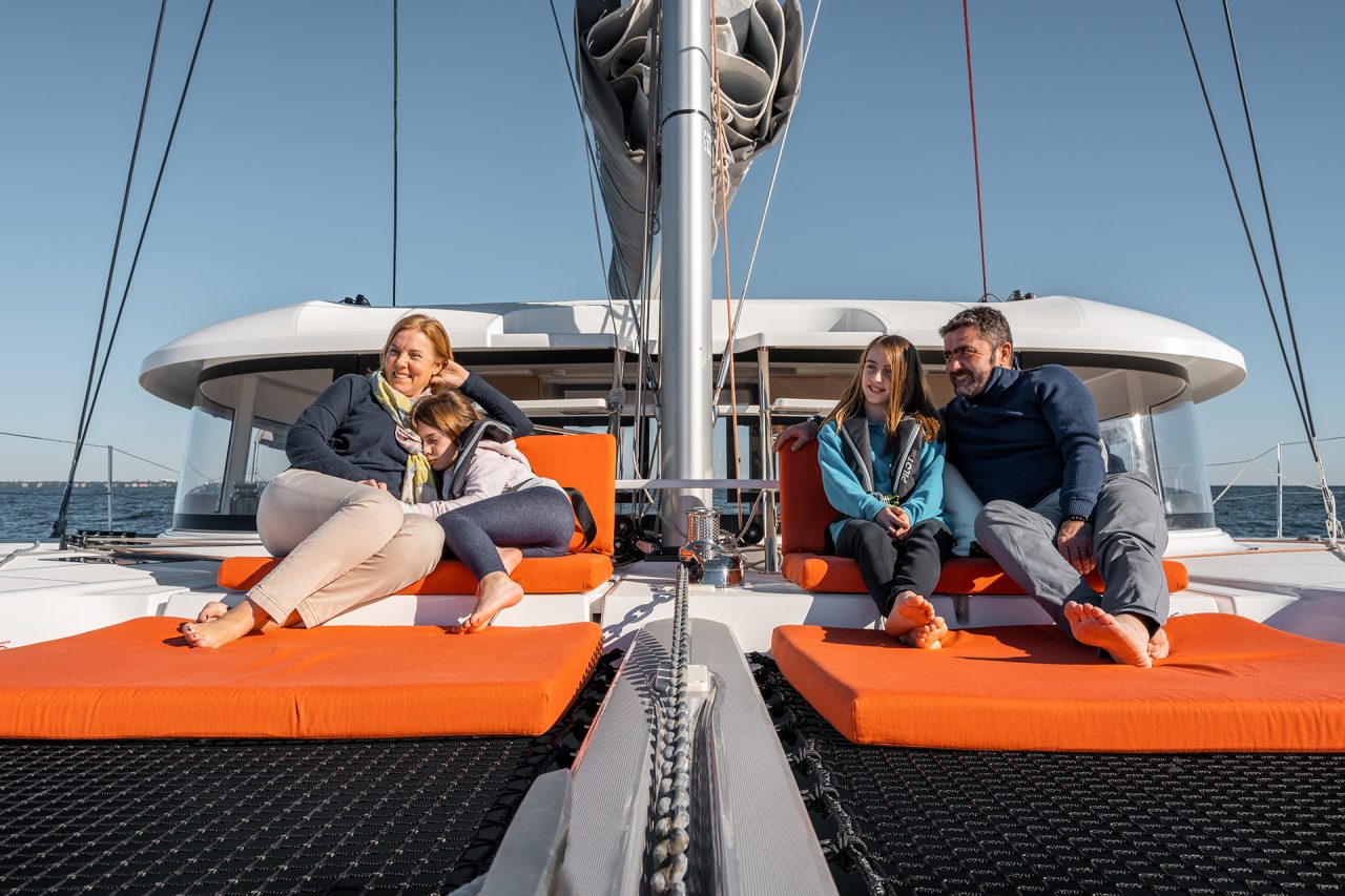 Family seated on the front deck on the Excess 14 sailing catamaran