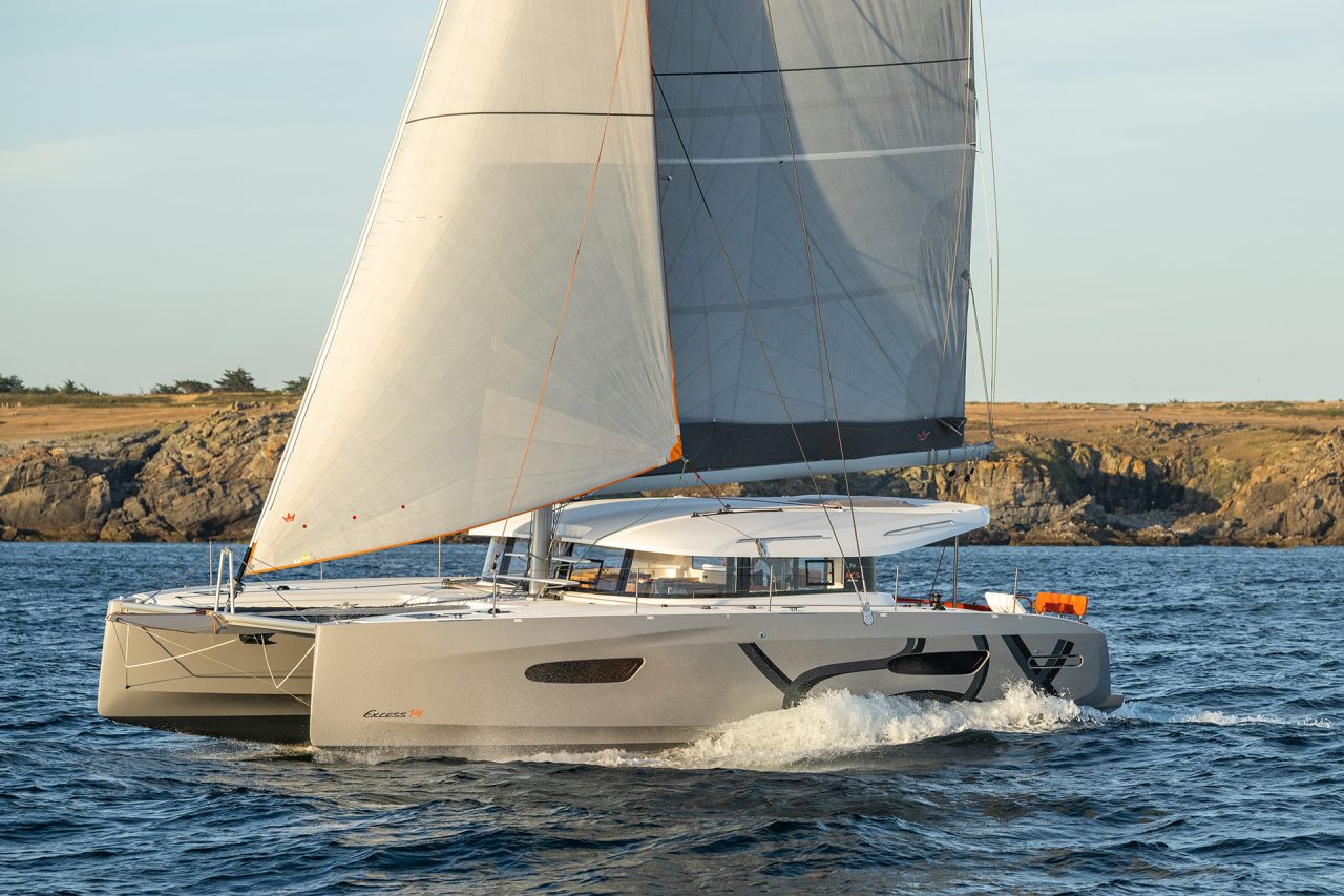 Excess 14 catamaran sailing along a rugged coastline