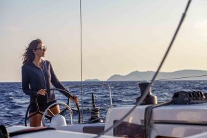 Woman at helm of a Jeanneau Sun Odyssey 410 monohull sailboat