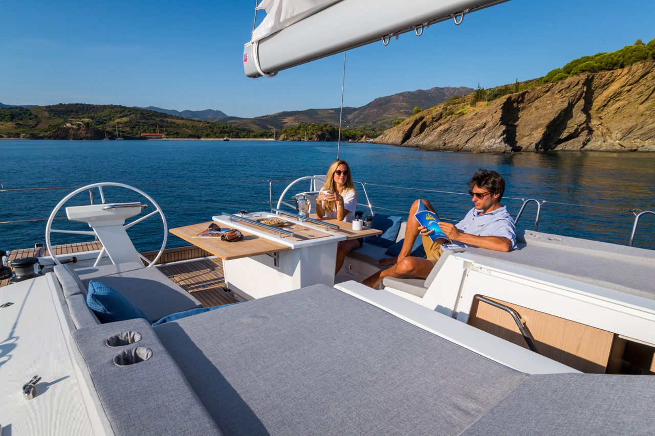 Couple lounging at the cockpit table on the Oceanis 46.1 sailboat